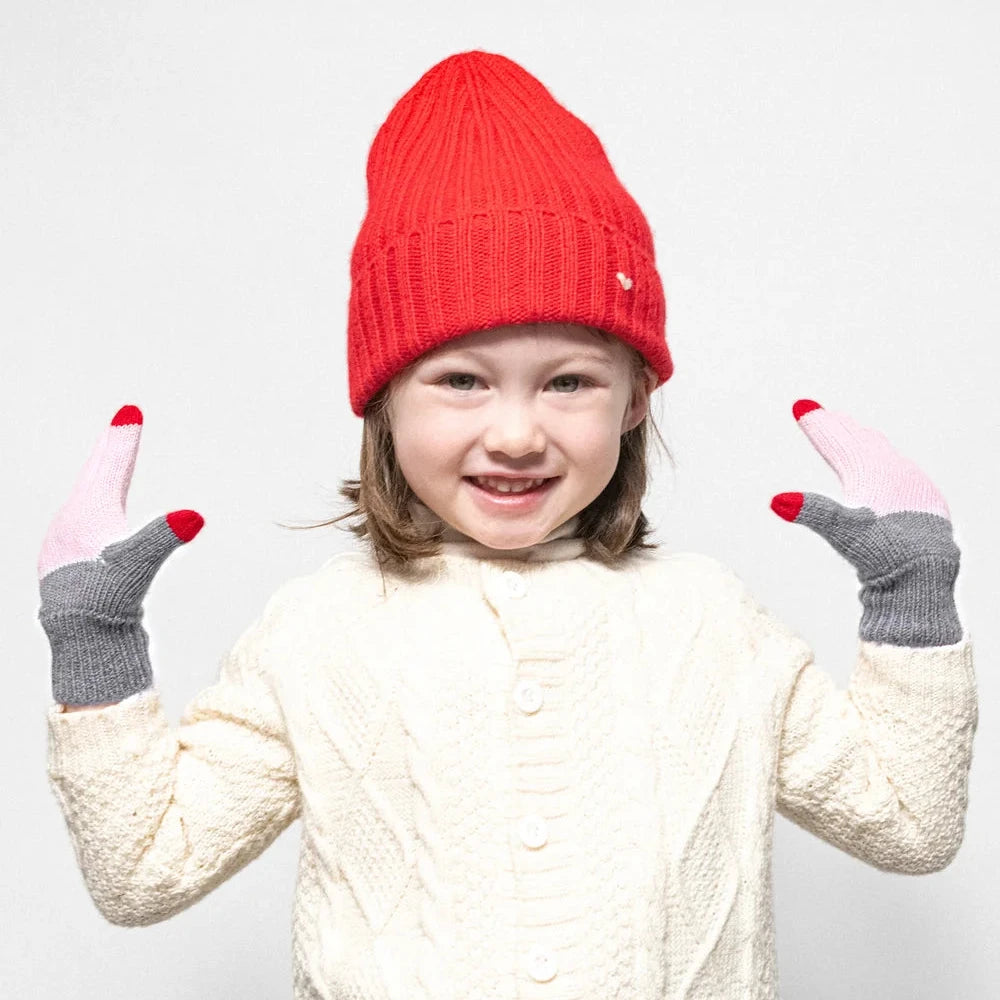 Child wearing a red beanie, white sweater, and blue jeans on a white background