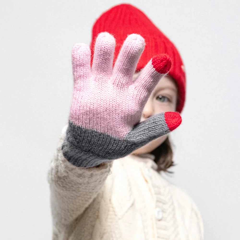 Person wearing a red beanie and pink and gray glove on a white background