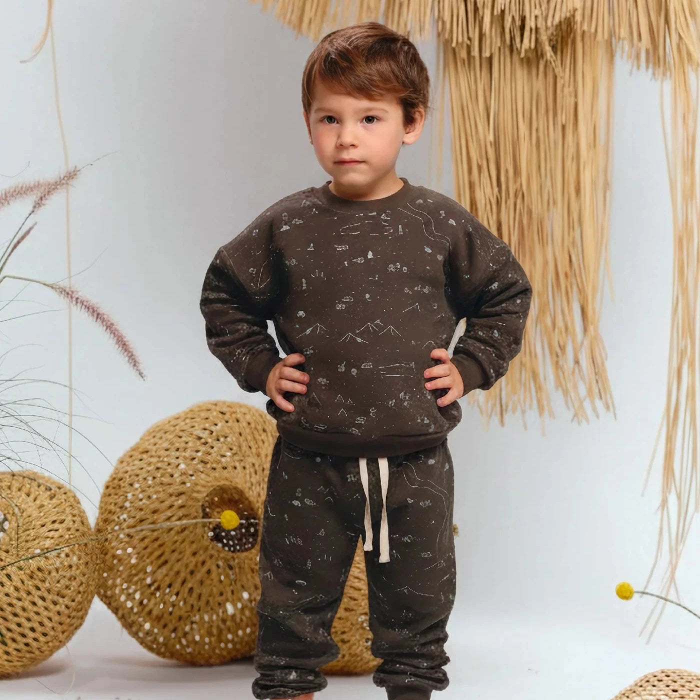 Child wearing a brown patterned outfit in a decorative setting.