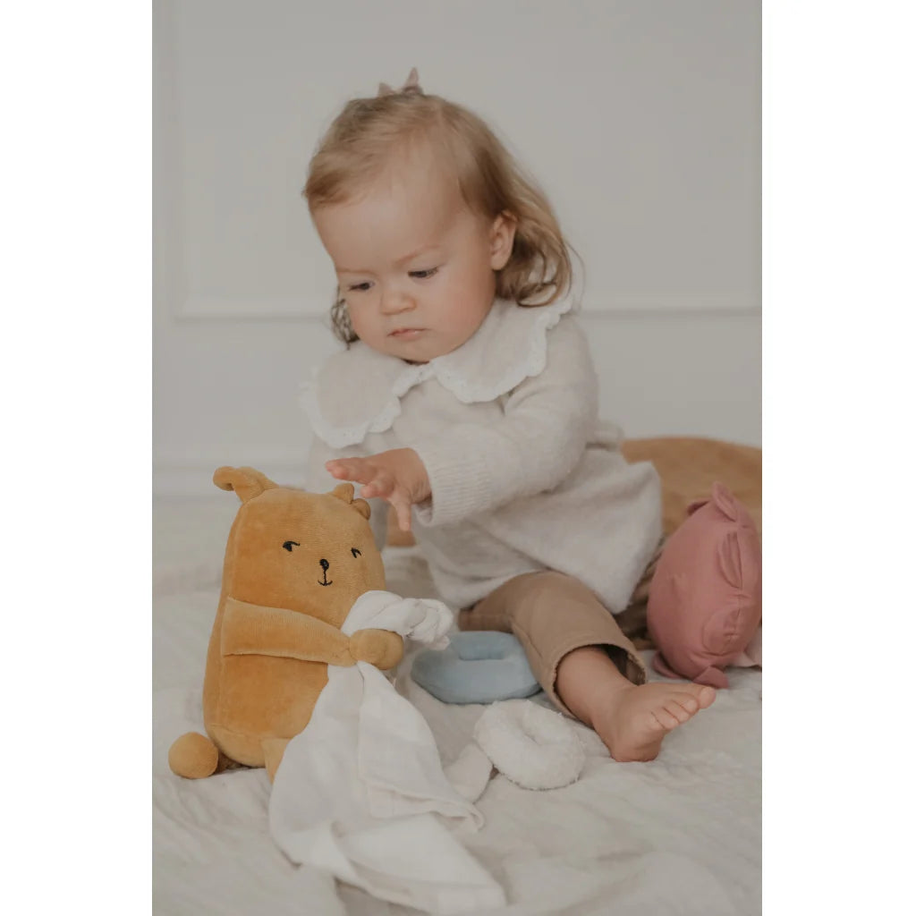 Child playing with a plush toy on a soft surface