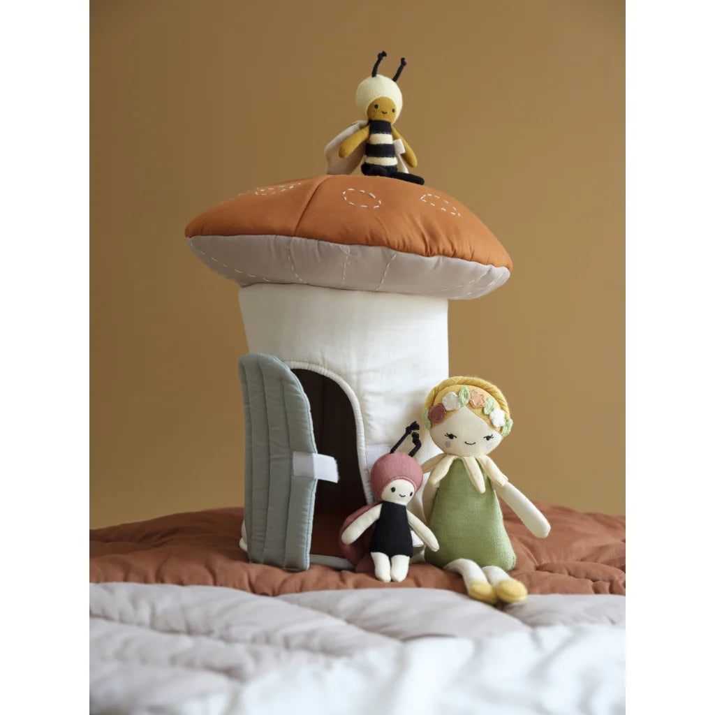Toy mushroom house with bee and doll on a soft surface