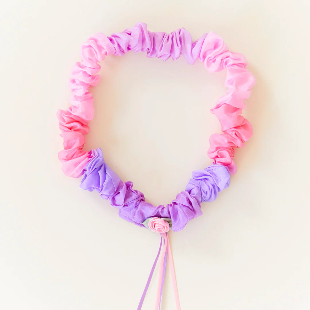 Silk garland made of pink and purple ruffled fabric on a light background