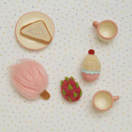Set of toy food items including bread, a cup, and a pink fruit on a patterned background