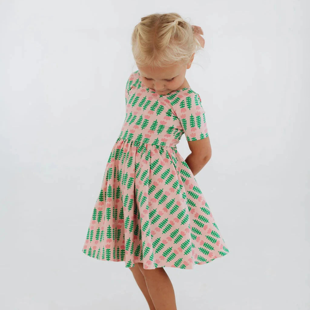 Child wearing a pink and green patterned dress on a white background