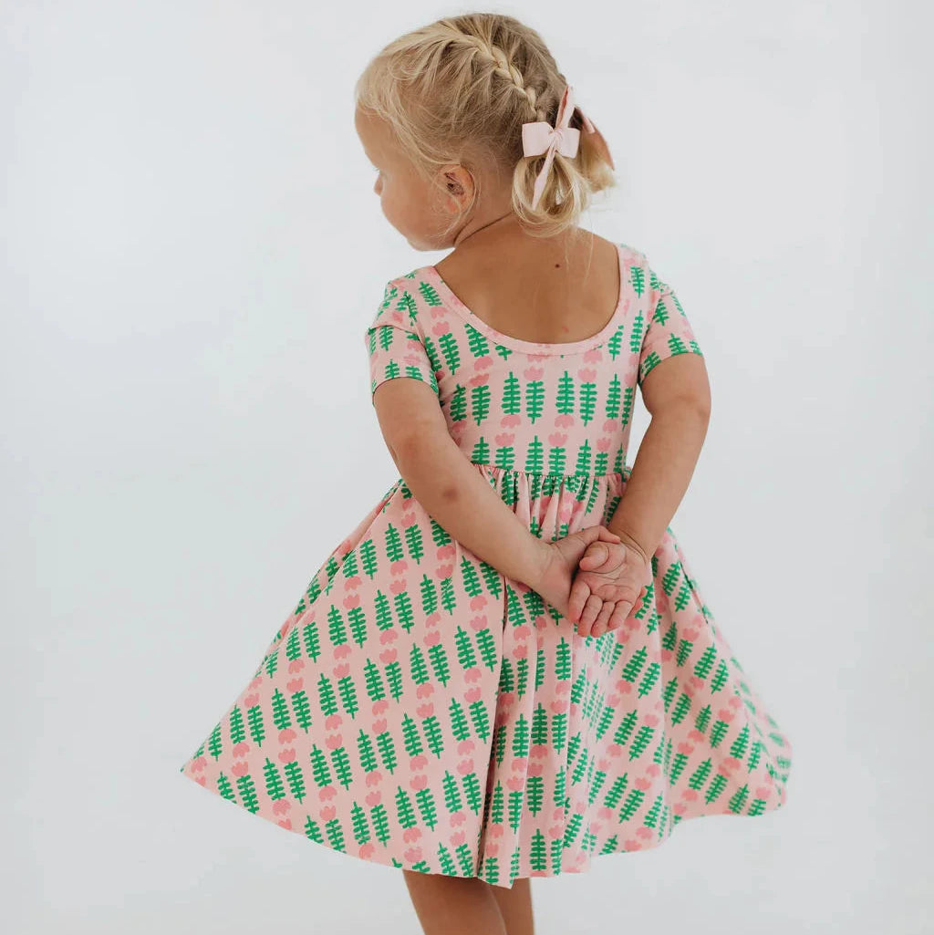 Child wearing a pink and green patterned dress on a white background