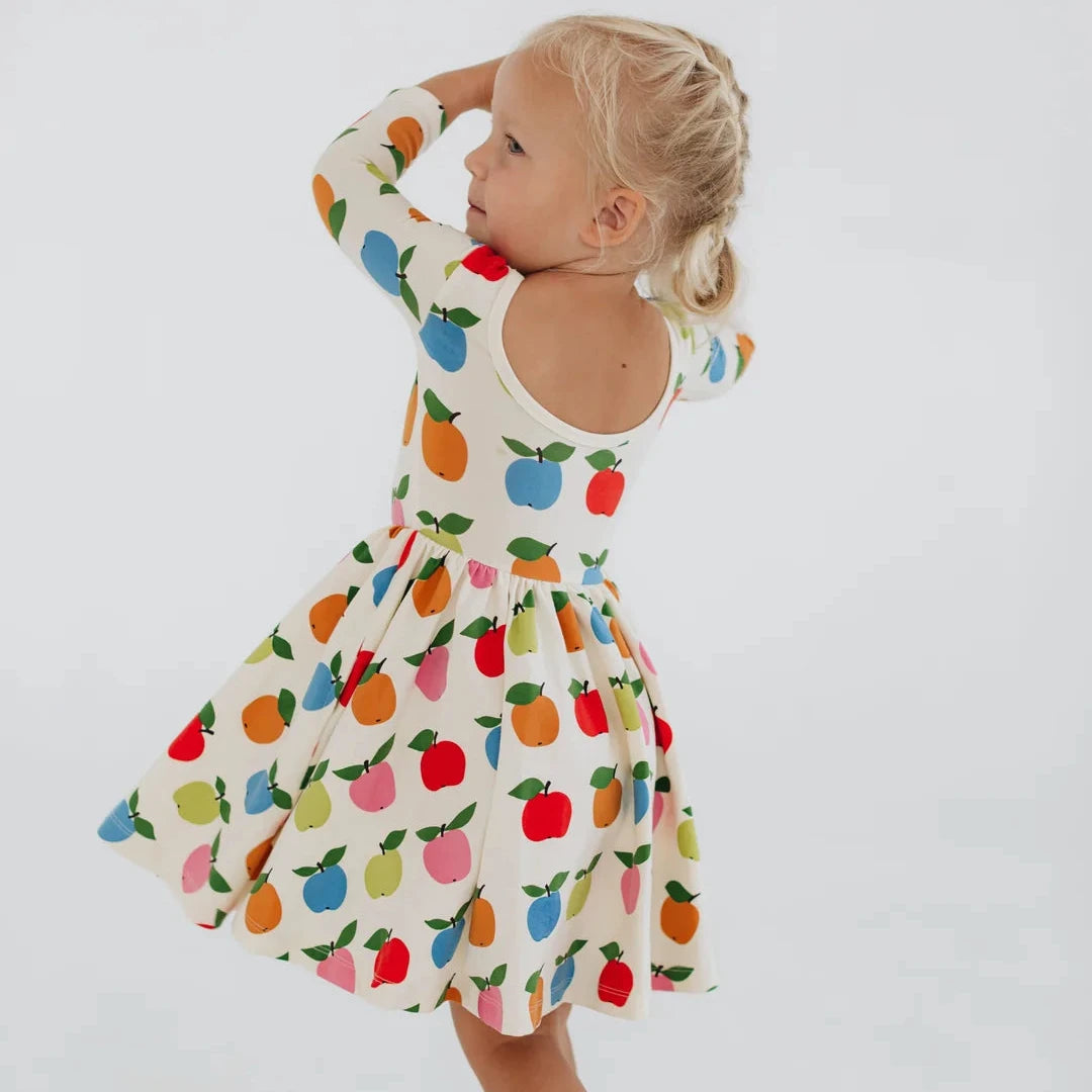 Child wearing a colorful fruit-patterned dress on a white background