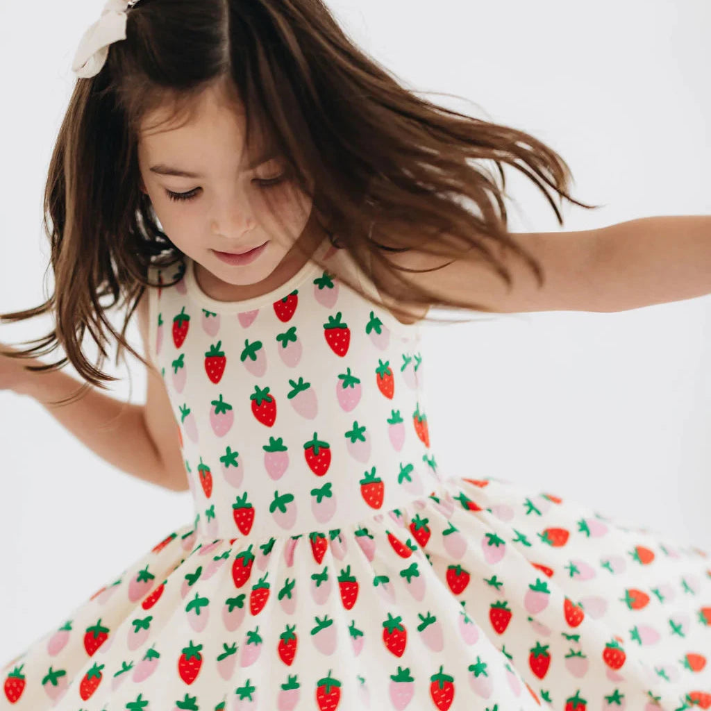 Young girl wearing a dress with strawberry pattern on a white background