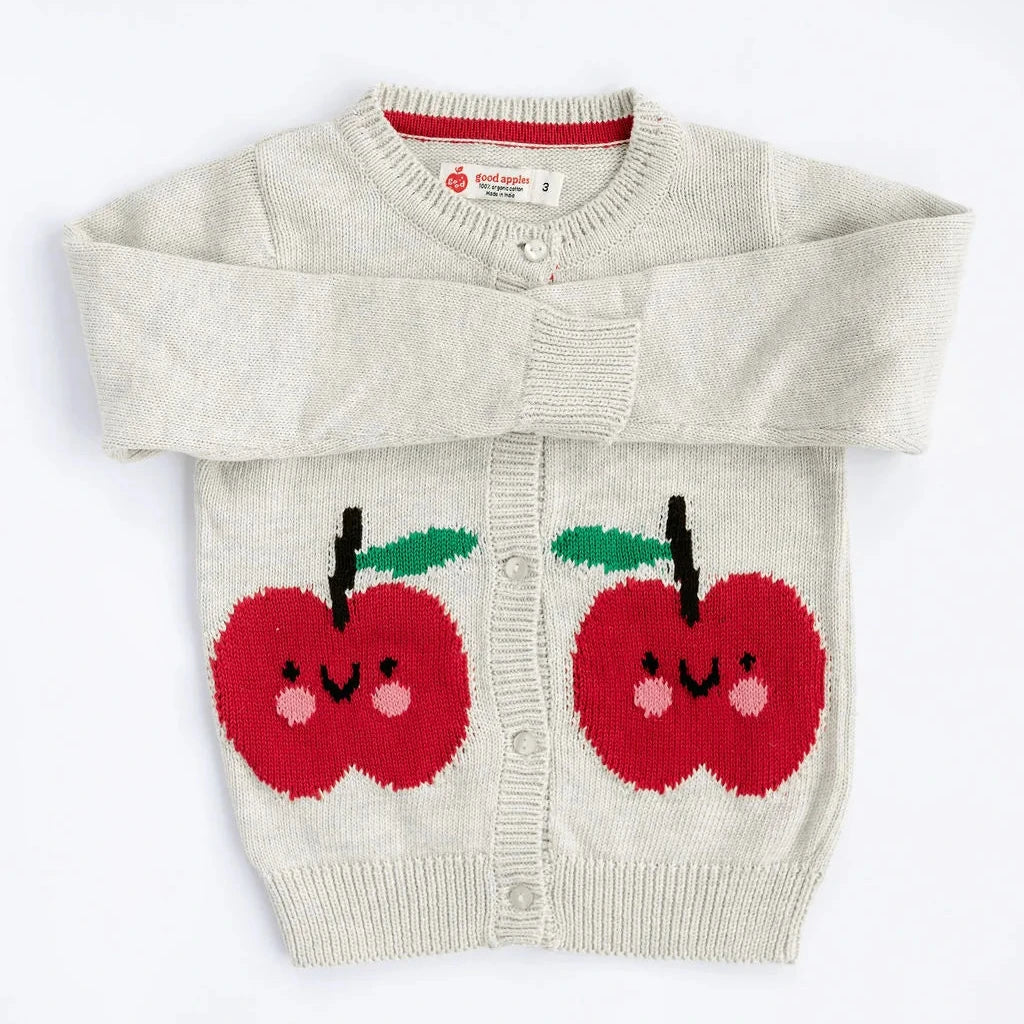 Child wearing a white sweater with a red apple design and a red and orange striped skirt on a white background