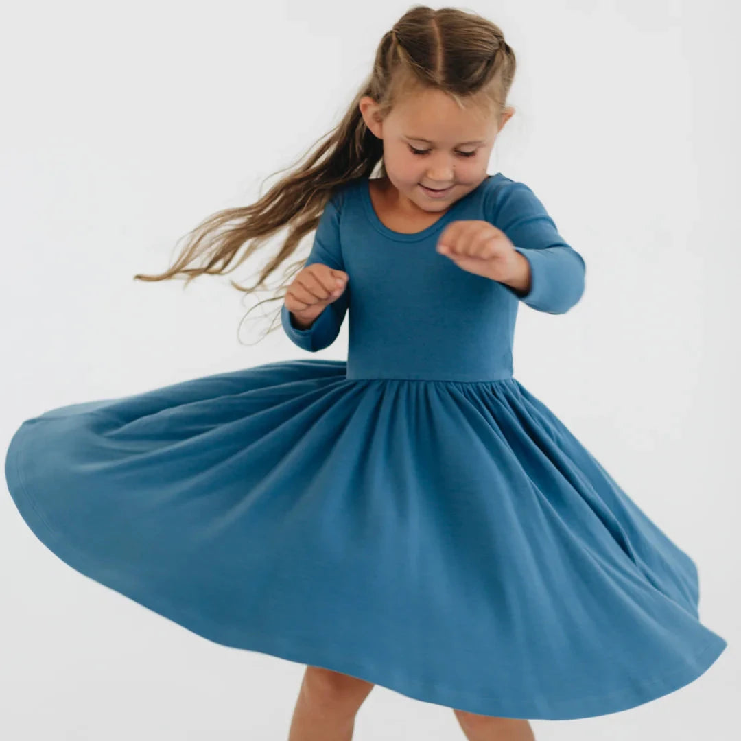 Young girl in a blue dress twirling on a white background