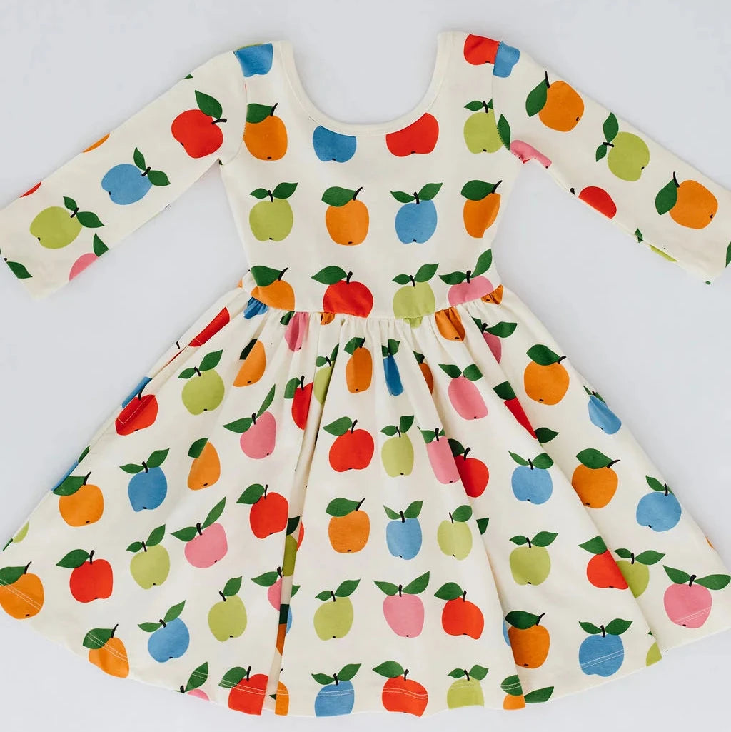 A long-sleeve dress with a colorful fruit print, featuring red apples, green apples, and blue apples on an off-white background.