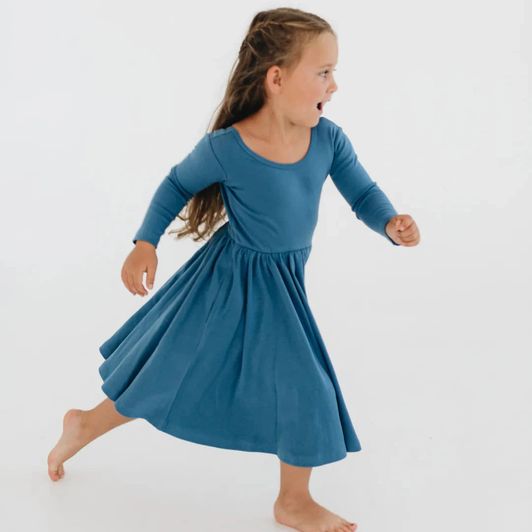 Young girl in a blue dress twirling on a white background