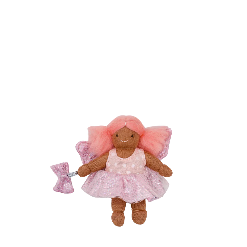 A small doll named Tulip the Tooth Fairy with pink hair, a sparkly fabric skirt, and a tooth-print top, being held by a person.