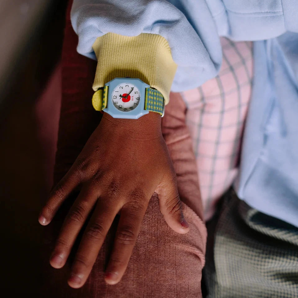 Child's hand with a colorful wrist watch featuring an apple print  on a dark surface.