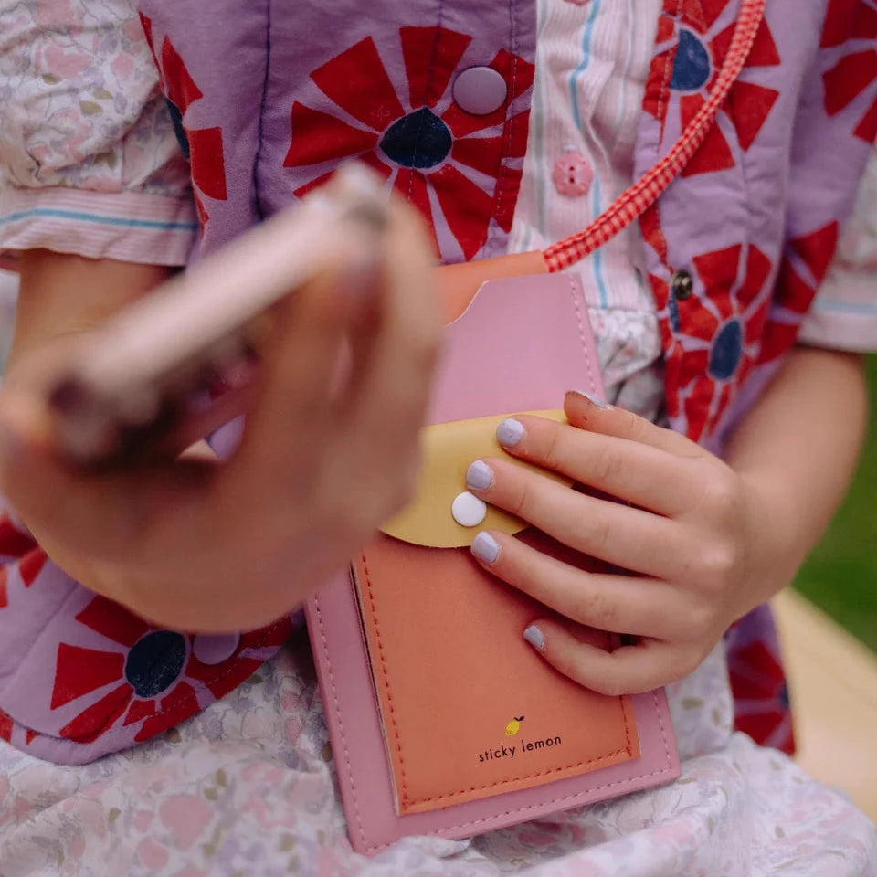 Person wearing a colorful outfit with a pink phone case