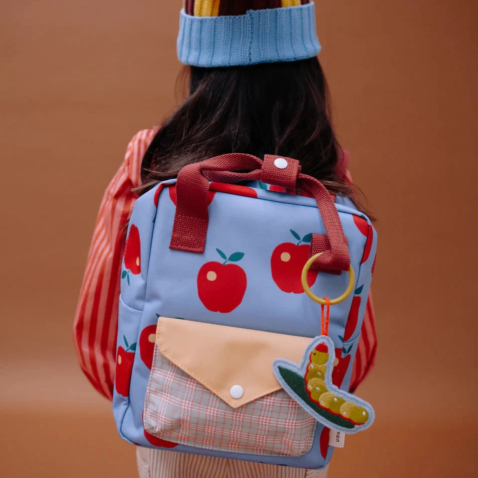 Person wearing a colorful backpack with apple design on a brown background