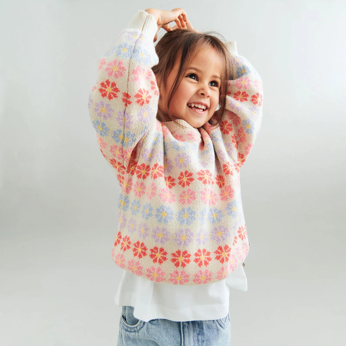 Child wearing a colorful floral-patterned sweater on a plain background
