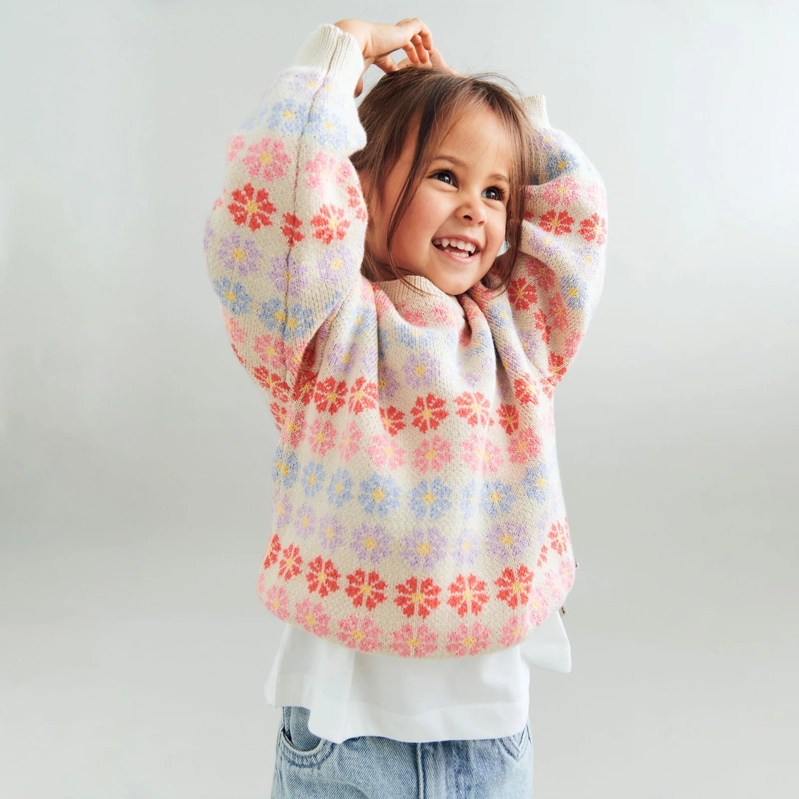 Child wearing a colorful floral-patterned sweater on a plain background