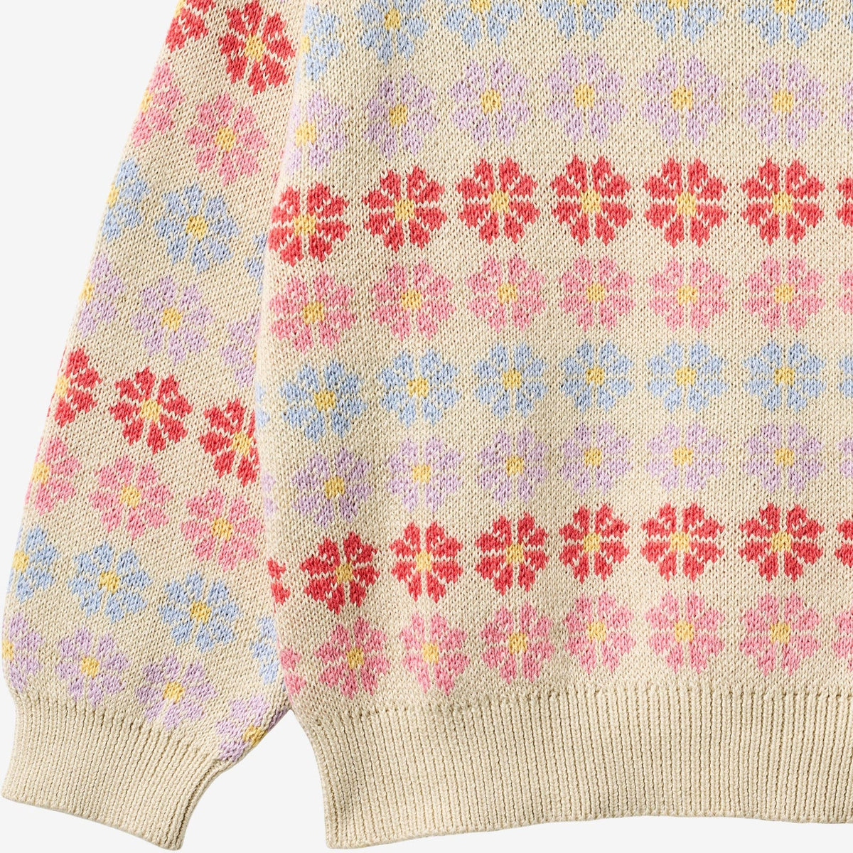 Close-up of a knitted fabric with a colorful flower pattern on a beige background