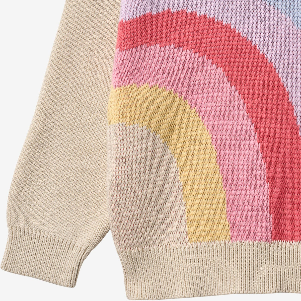Close-up of a knit sweater with a rainbow design on a light background