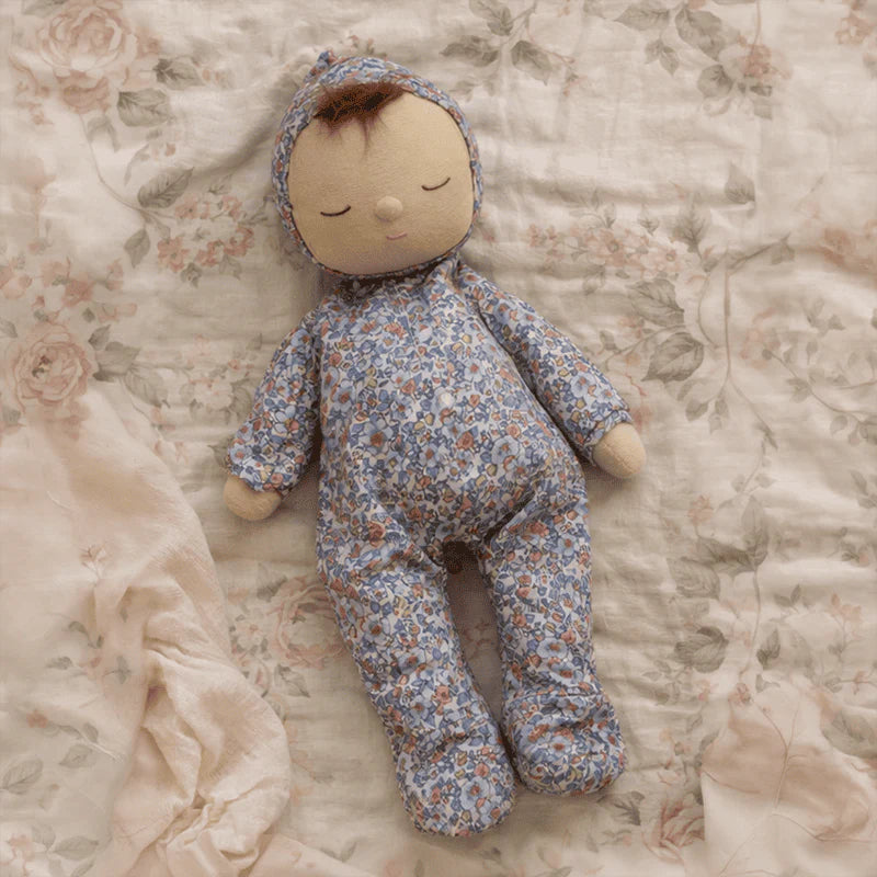 Baby doll in floral outfit lying on a floral blanket