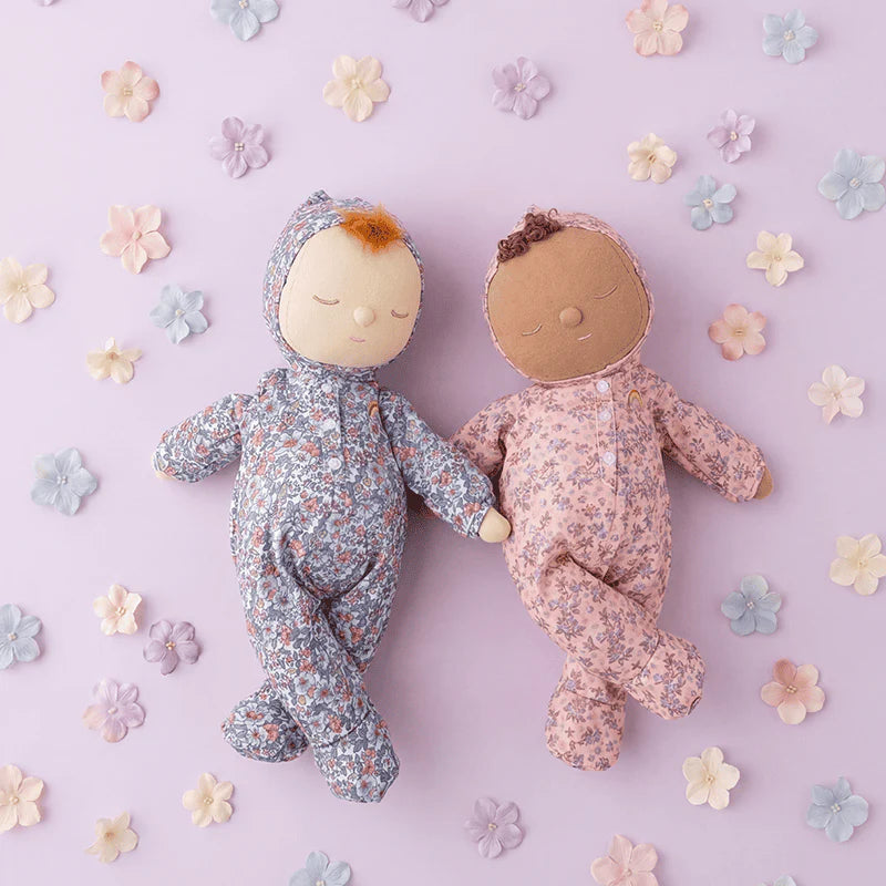 Two dolls in floral outfits on a light purple background with flowers.