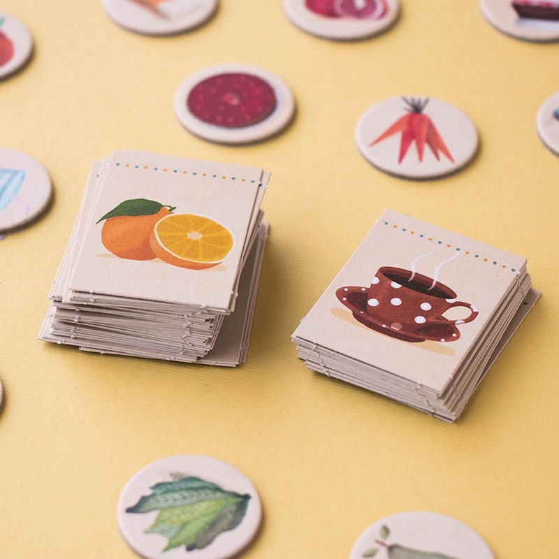 Stacks of playing cards with fruit and tea cup illustrations on a yellow background.