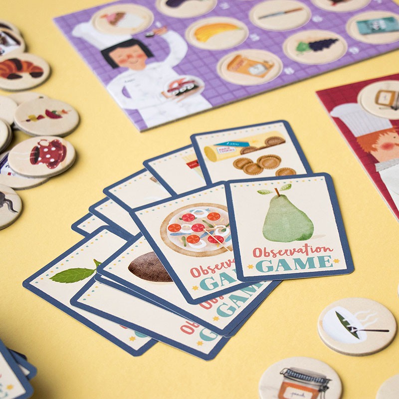 Board game components including cards, pieces, and a box on a yellow background