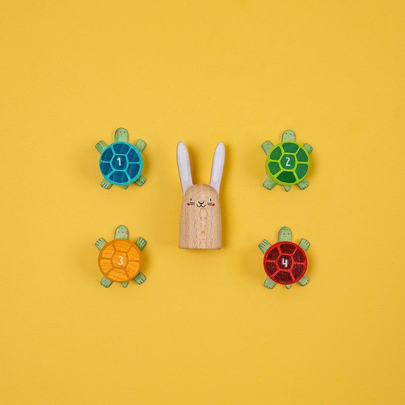 Four colorful turtle-shaped numbers with a wooden rabbit toy on a yellow background