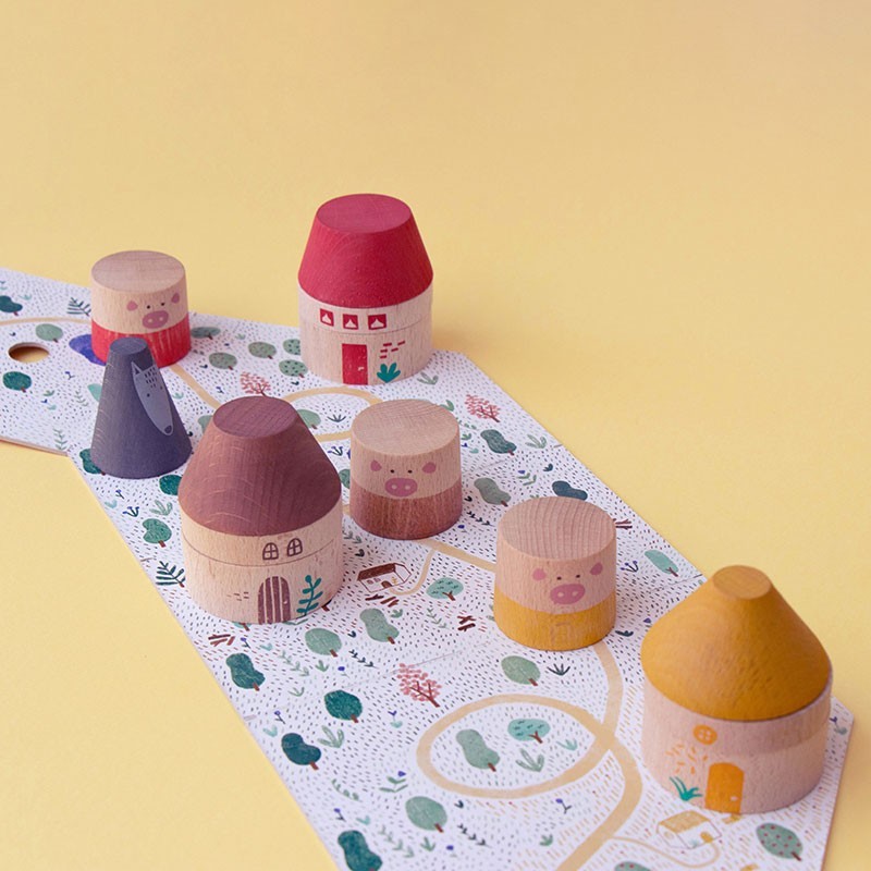 Set of colorful wooden toy houses on a patterned mat with a yellow background