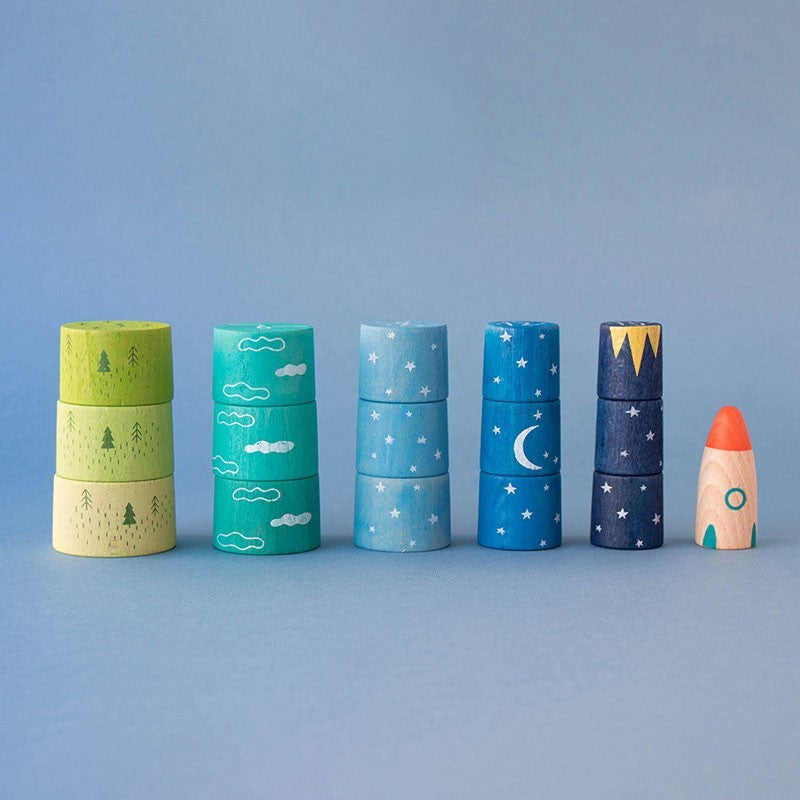 Set of colorful wooden stacking toys with nature and space designs on a blue background