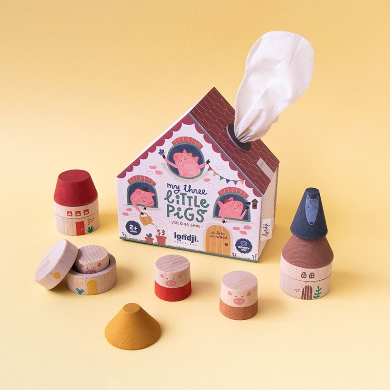 Wooden toy houses with a box labeled 'My Three Little Pigs' on a yellow background