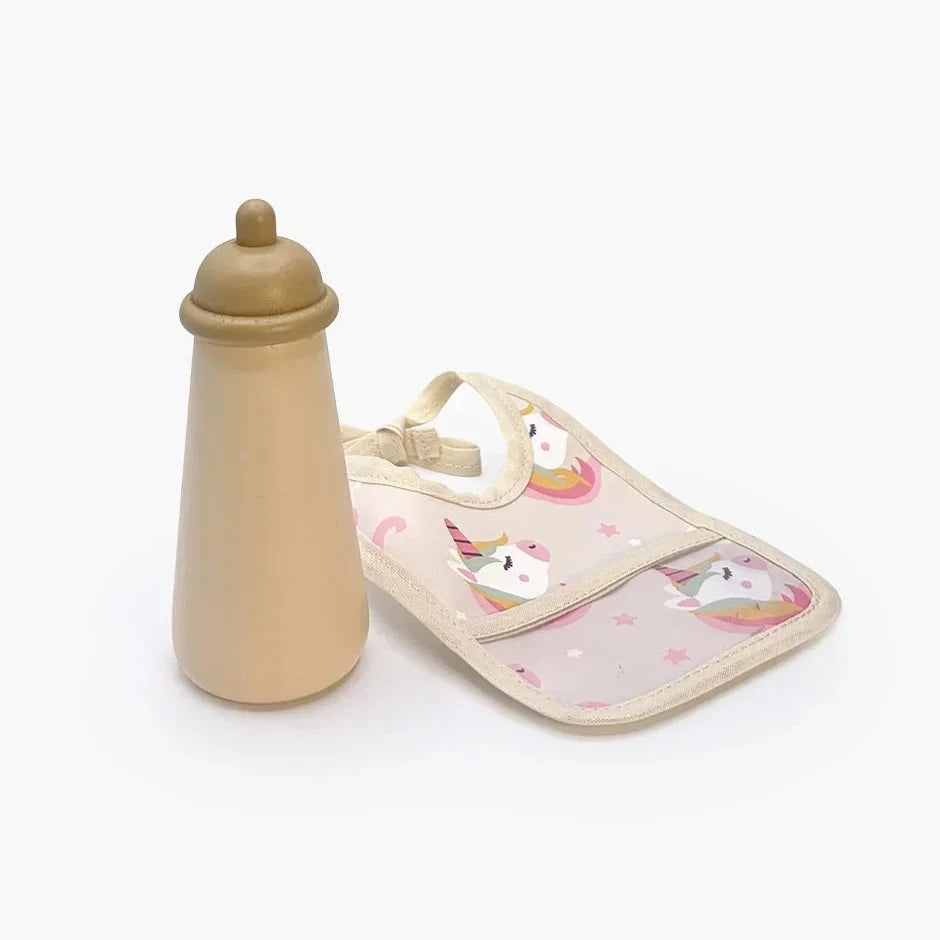 A baby bottle and matching bib set on a clean white background. The bottle is solid beige, and the bib features a light pink background with white unicorn illustrations and small pink hearts.