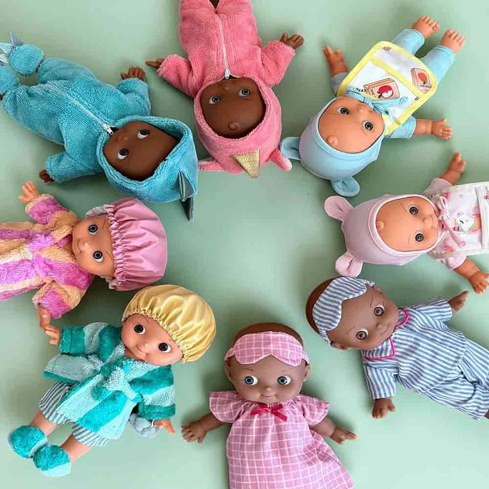 A group of baby dolls dressed in colorful clothing, arranged in a circle on a light mint green background.