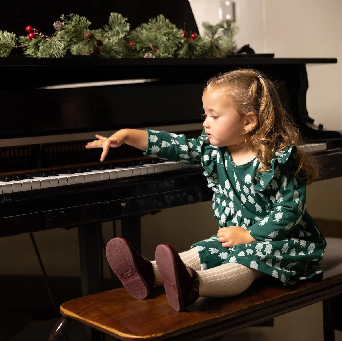 Child sitting at piano in tree printed dress