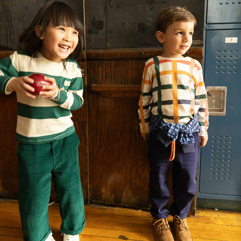 Two children standing in front of a locker, one holding an apple.