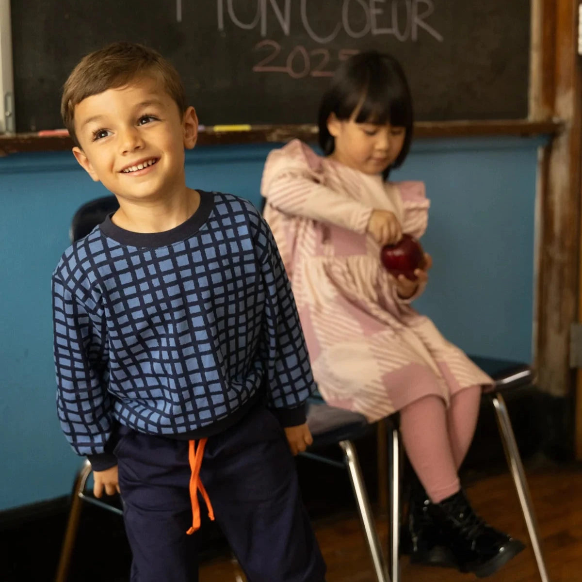 two children in a classroom wearing fall clothing