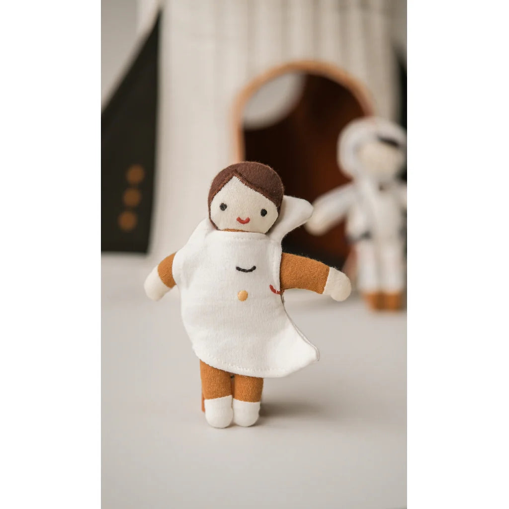 Small plush toy with a moon outfit and brown arms and legs on a light surface.