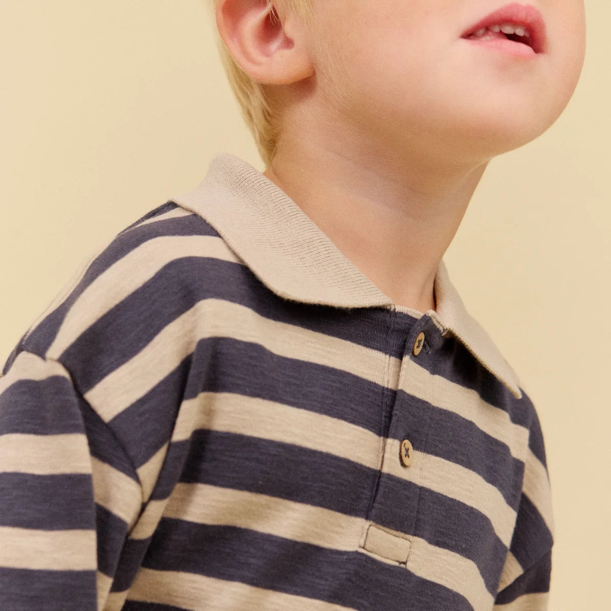 Child wearing a striped shirt on a beige background