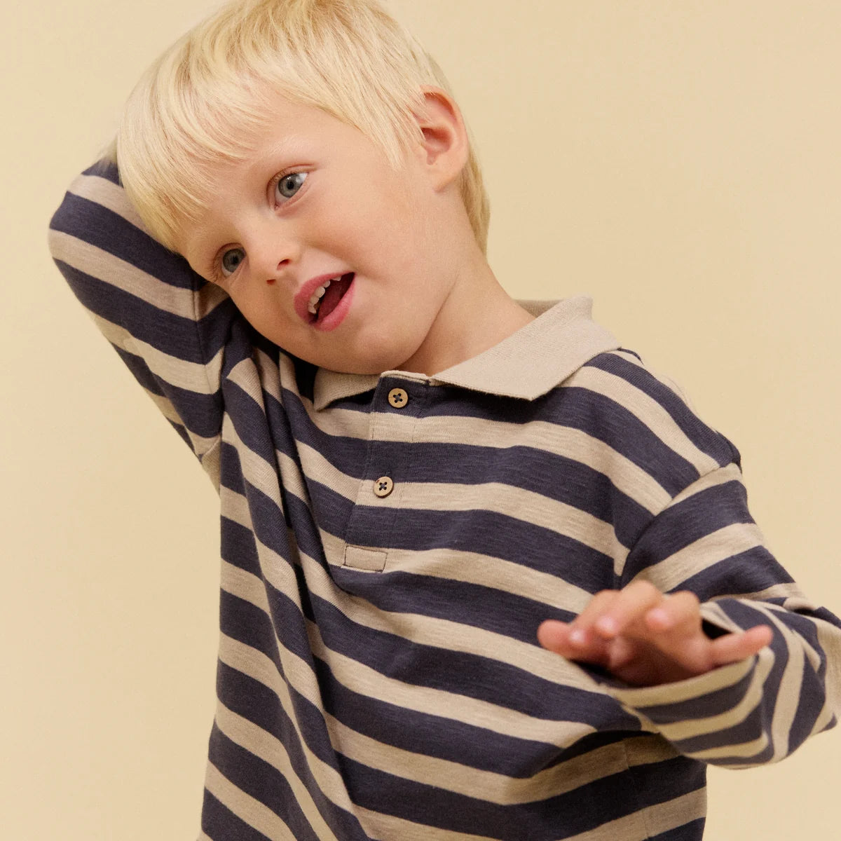 Child wearing a striped shirt on a beige background