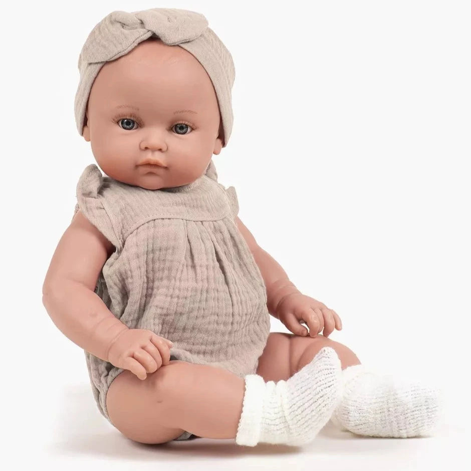 Baby doll wearing a beige outfit with a headband on a white background