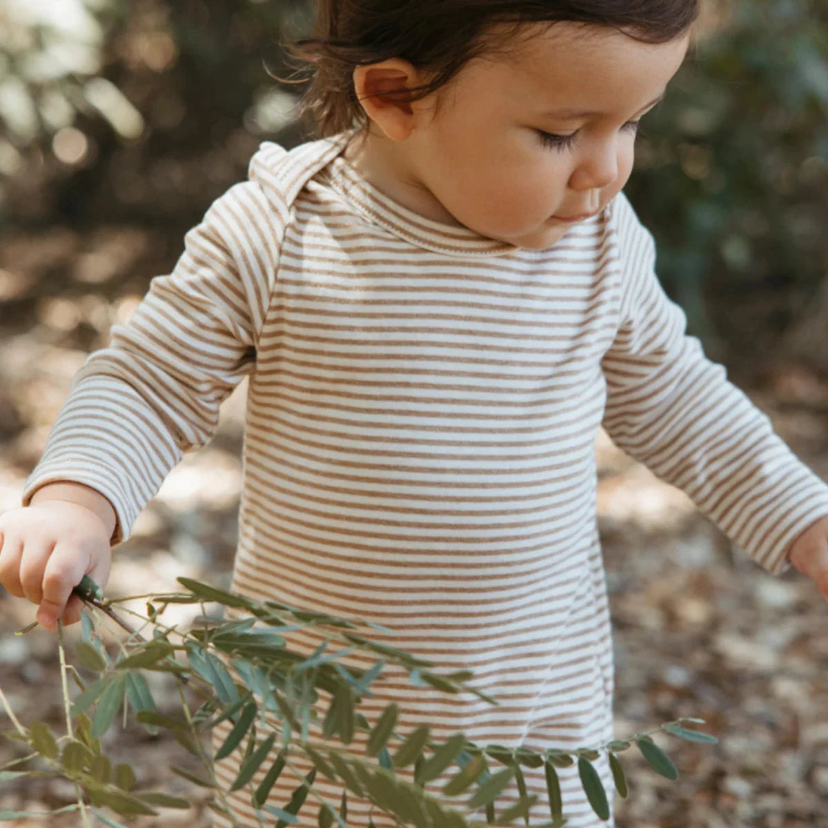 Child in a striped outfit standing in a natural setting