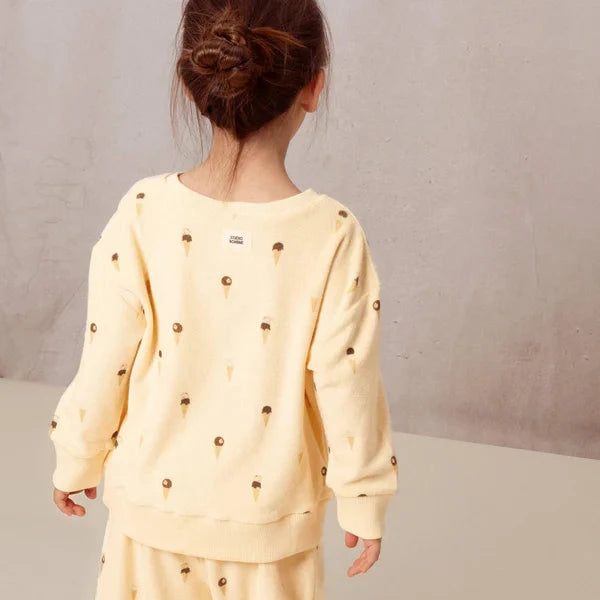 Child wearing a yellow outfit with black patterns on a neutral background