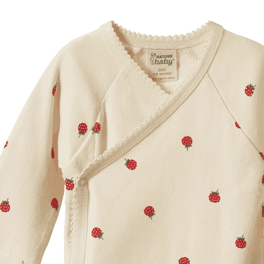 A close-up of a baby wrap in cream with a radish print. The brand label 'Nature baby' is visible inside the collar.