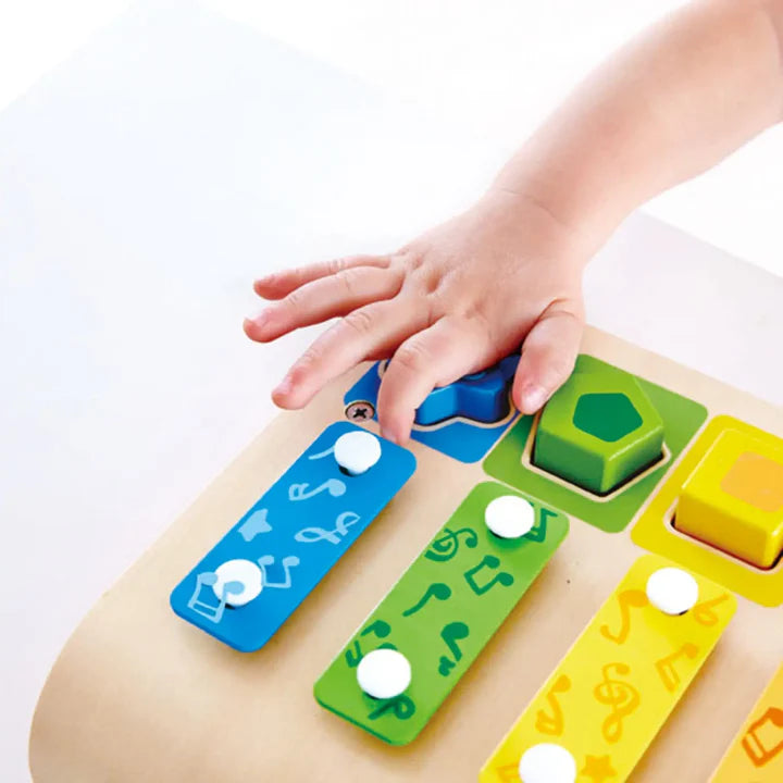 Colorful musical toy with buttons being pressed by a child's hand on a white background