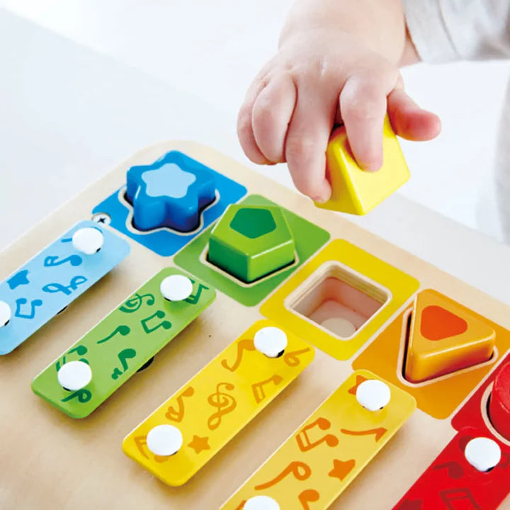 Child's hand interacting with a colorful wooden shape sorting toy.