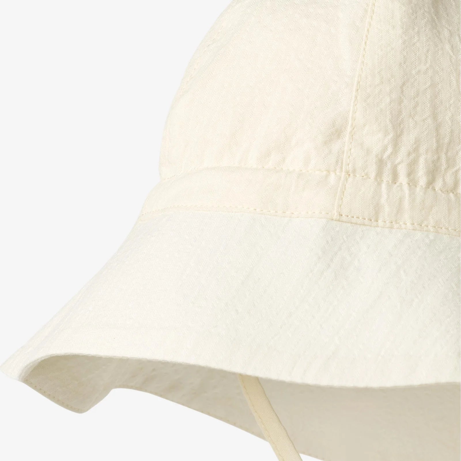 Beige baby sun hat with ties on a light gray background