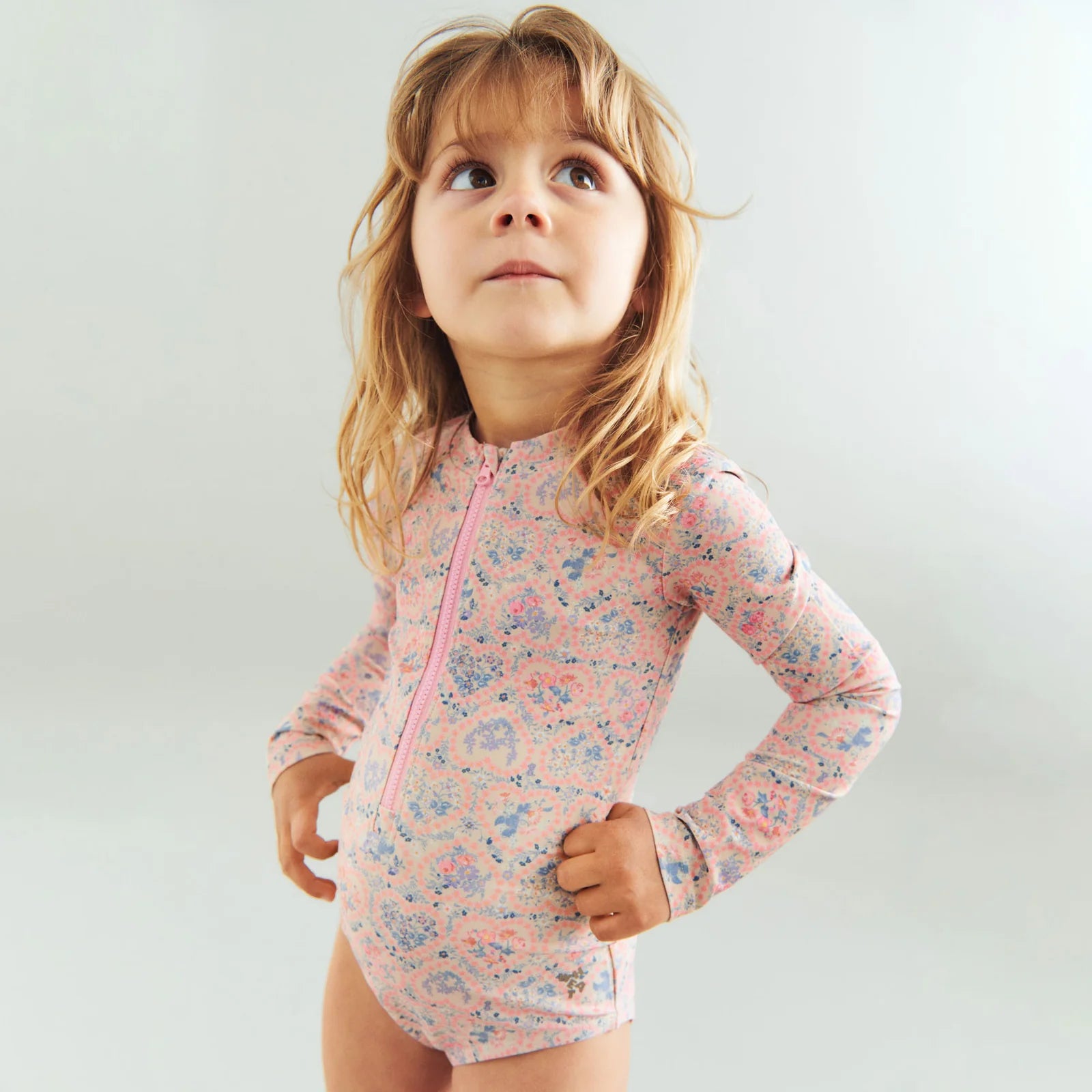 Child wearing a floral swimsuit with a white background