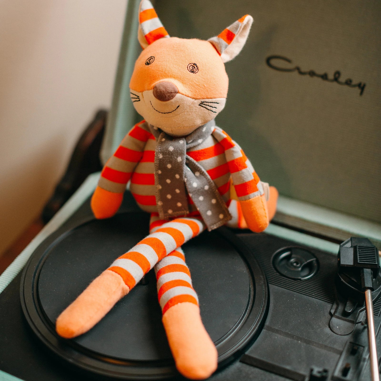 Plush toy fox with orange and gray striped body on a white background