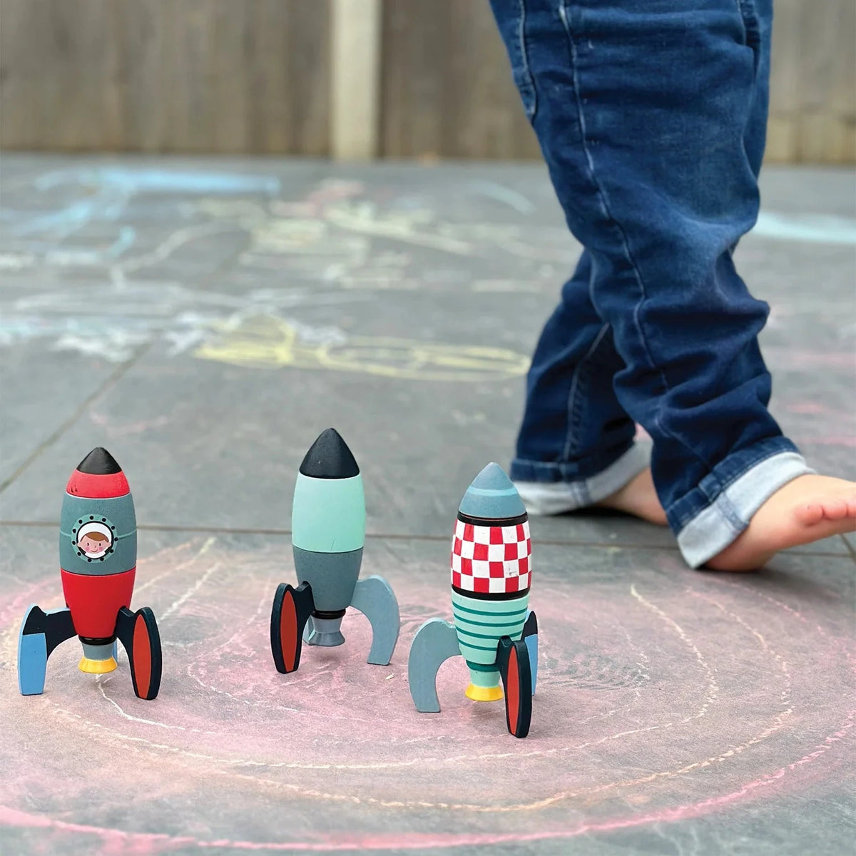 Child playing with toy rockets on a chalk-drawn circle outdoors.