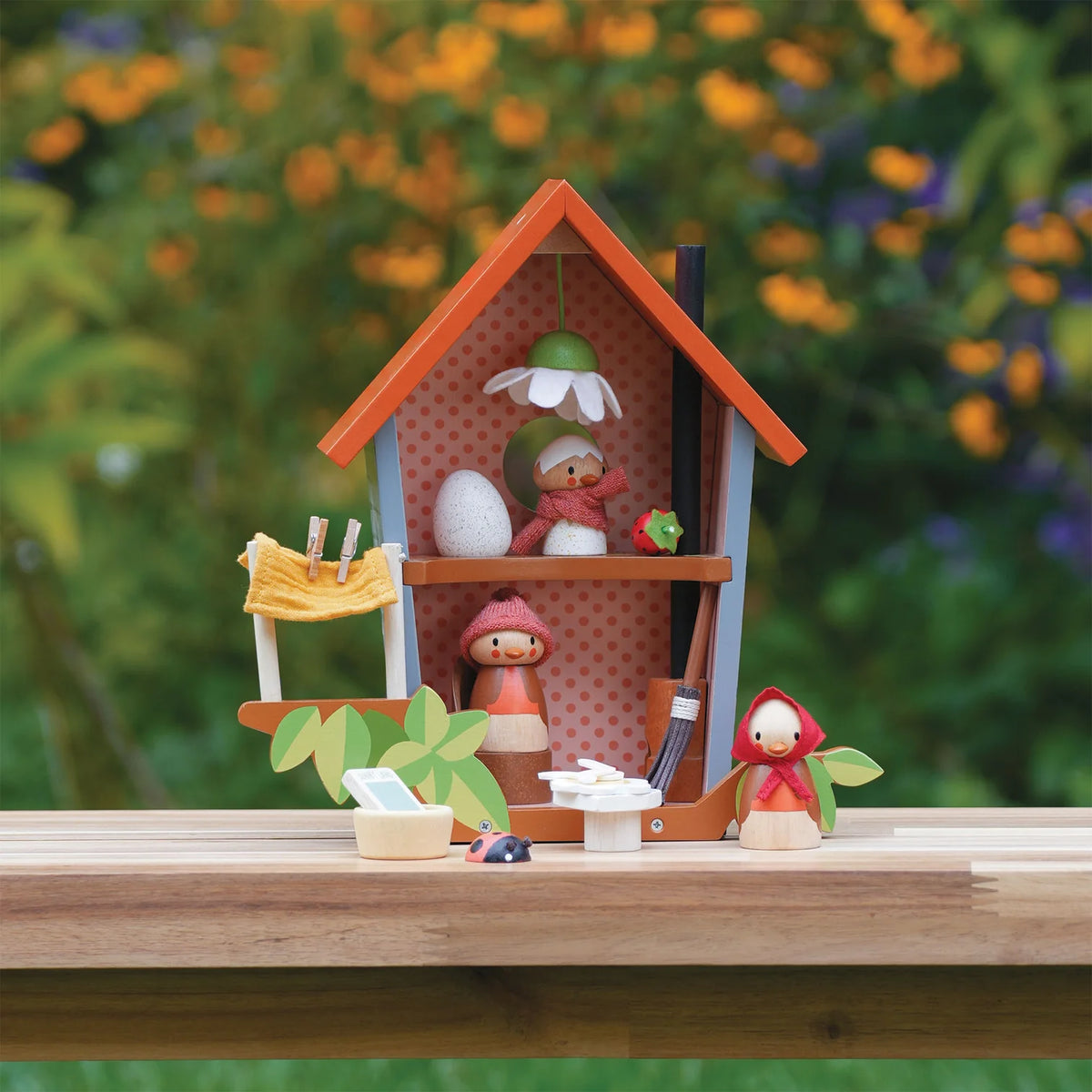 Wooden toy set with a house and characters on a wooden surface with a blurred natural background